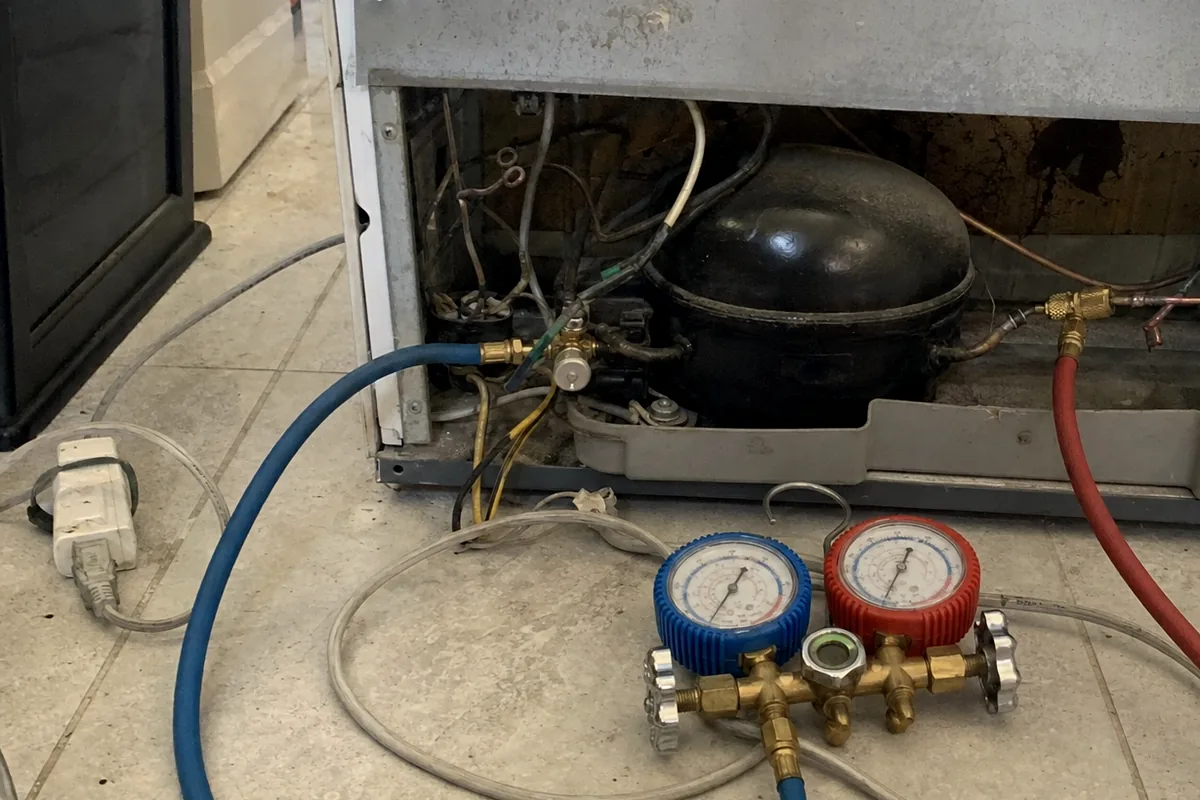 A close view of copper suction and discharge lines running from a compressor, gauge hoses attached